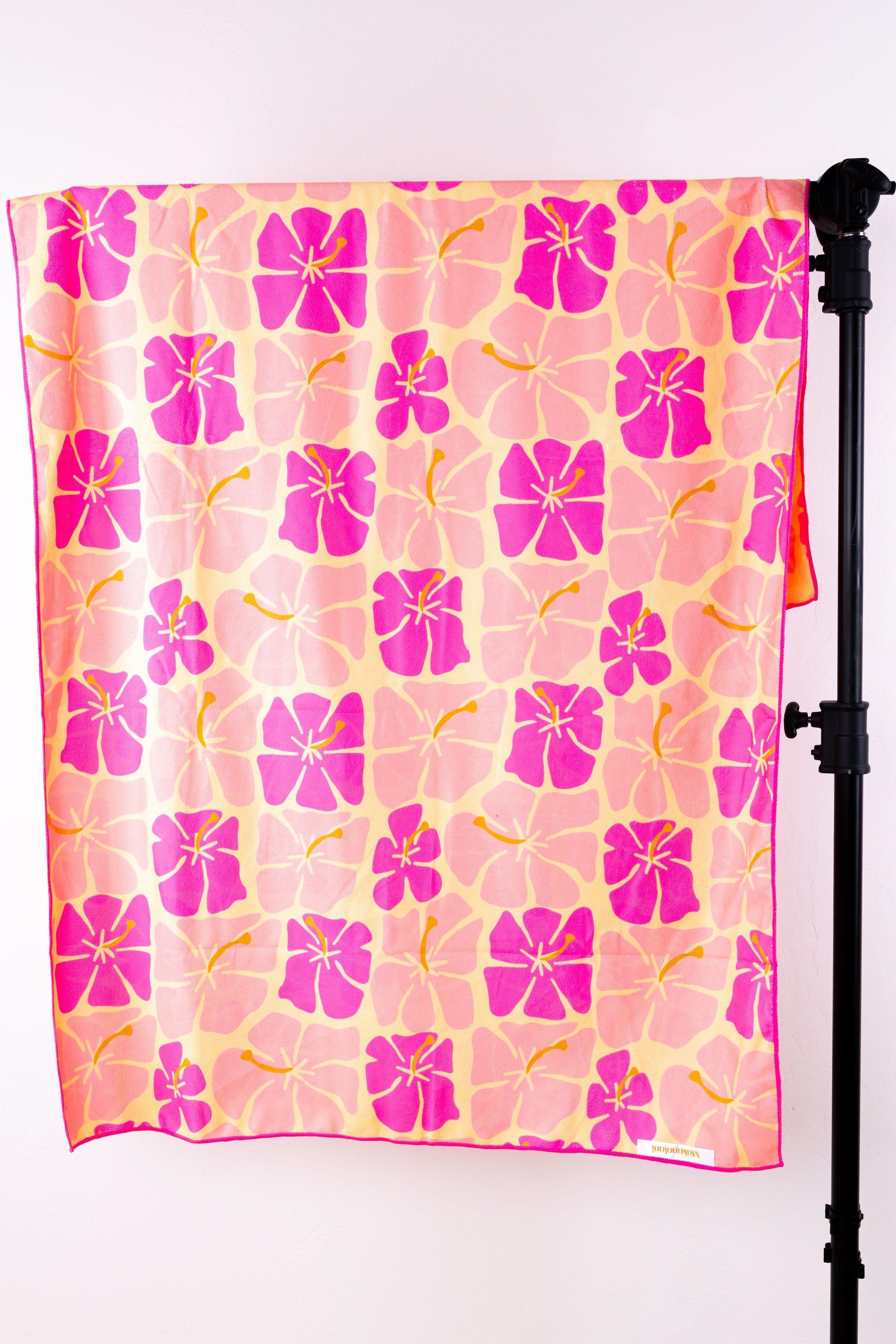 Brightly colored retro hibiscus printed beach towel drapped over a rack