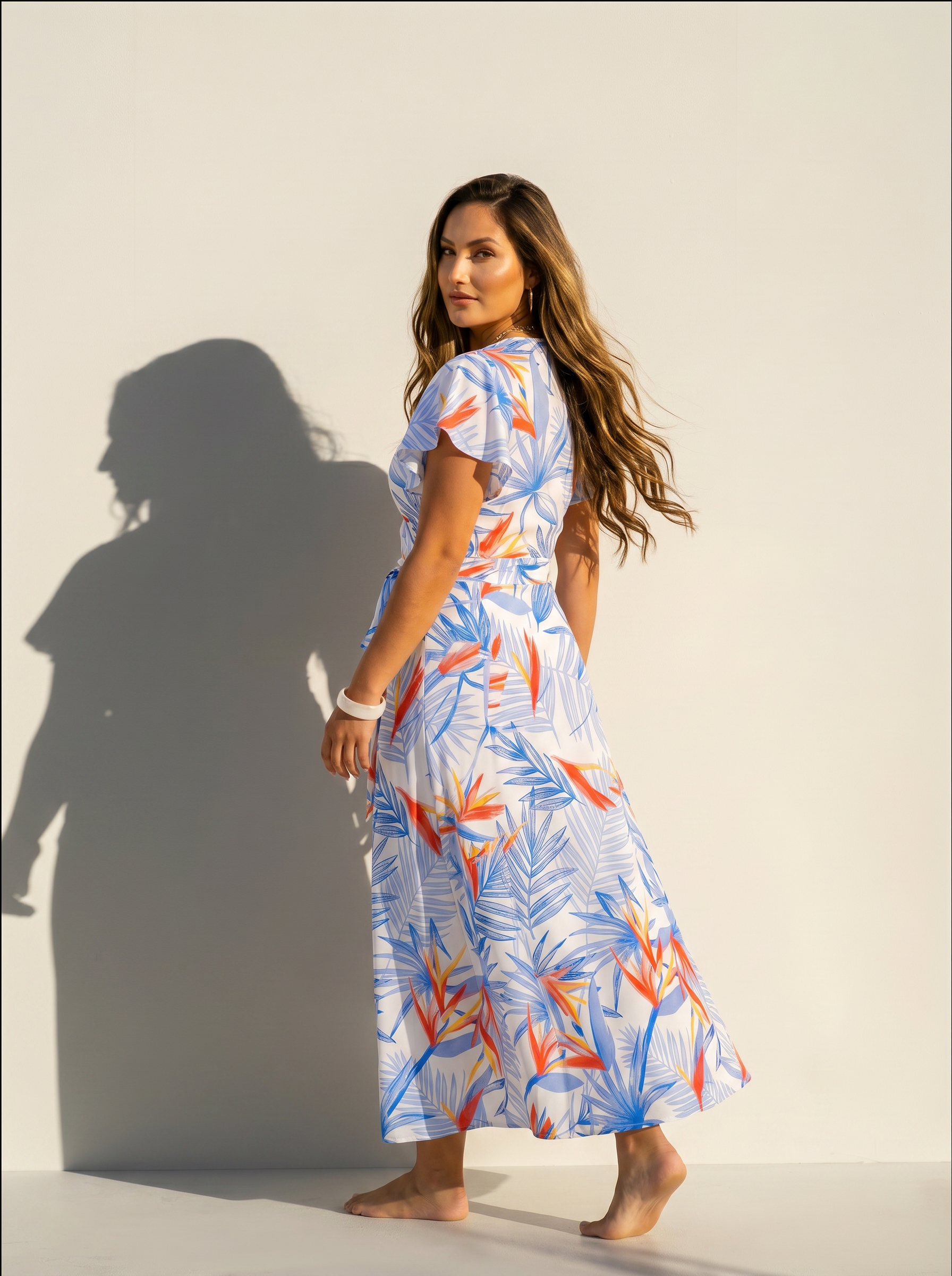 Back view of a women wearing a birds of paradise print wrap dress on a white background