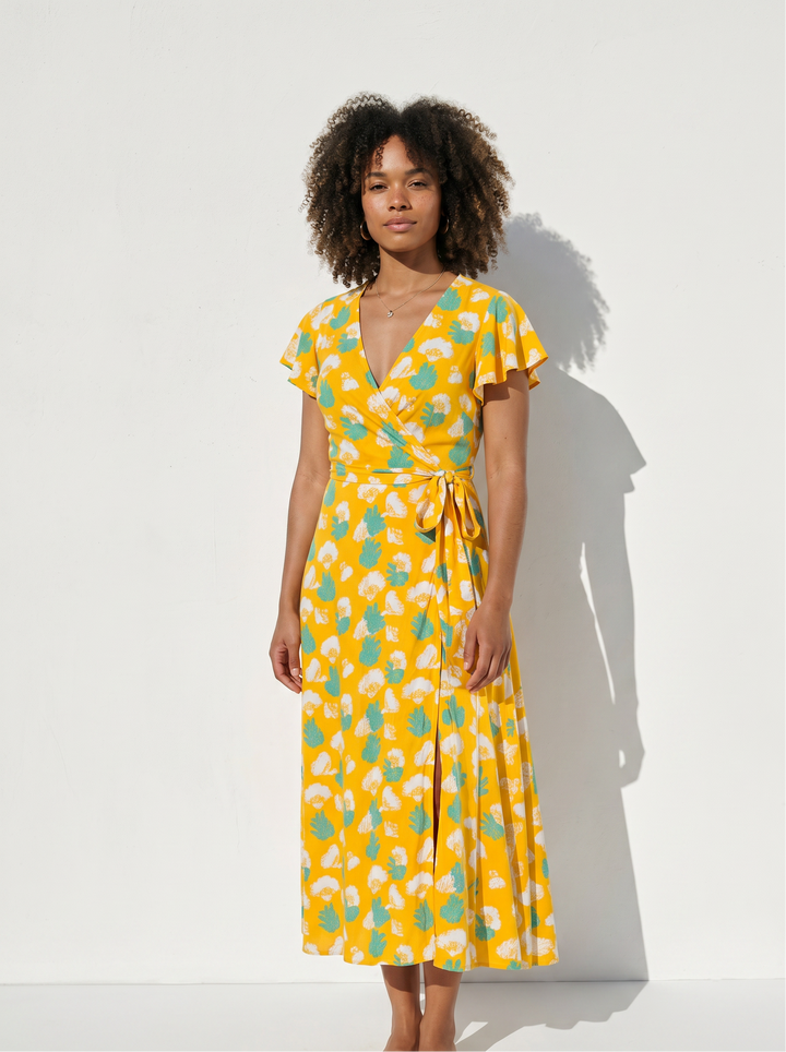 Full body view of women wearing yellow gingko print wrap dress on a white background