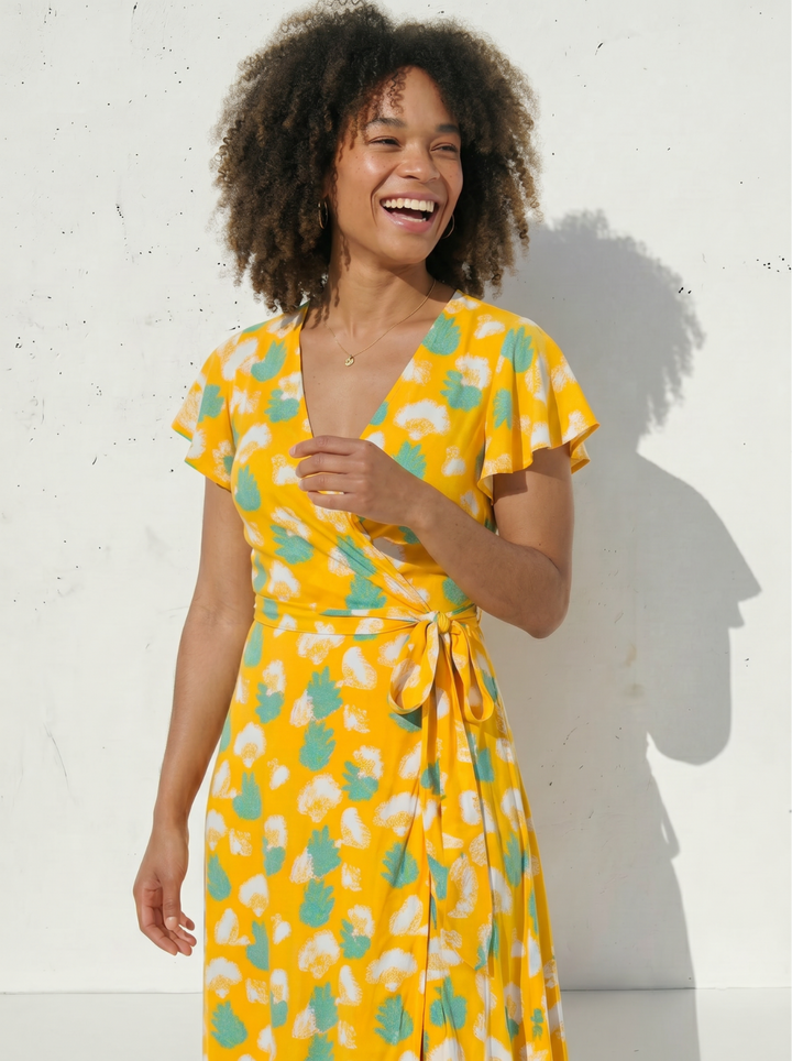Women wearing yellow gingko print wrap dress on a white background