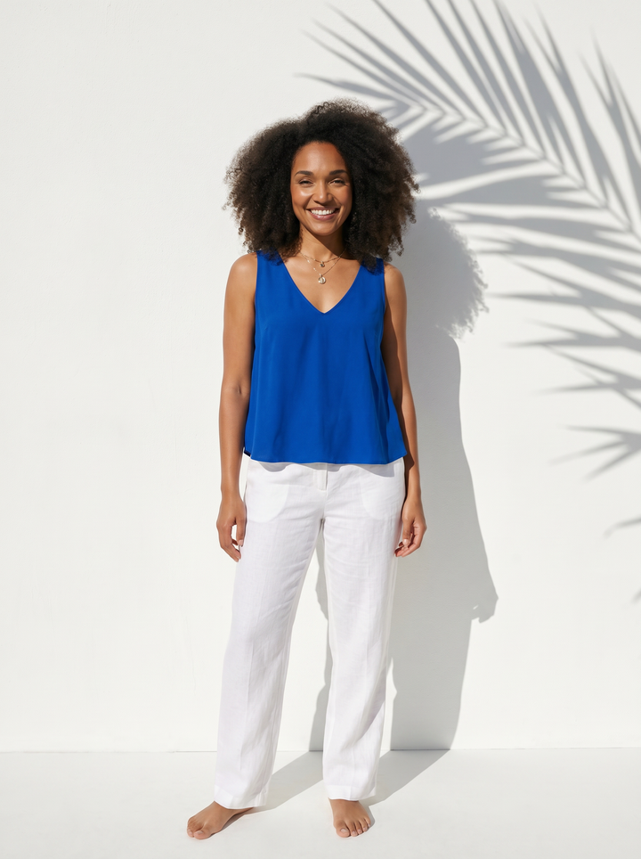 Women wearing blue tank top blouse and white pants on a white background