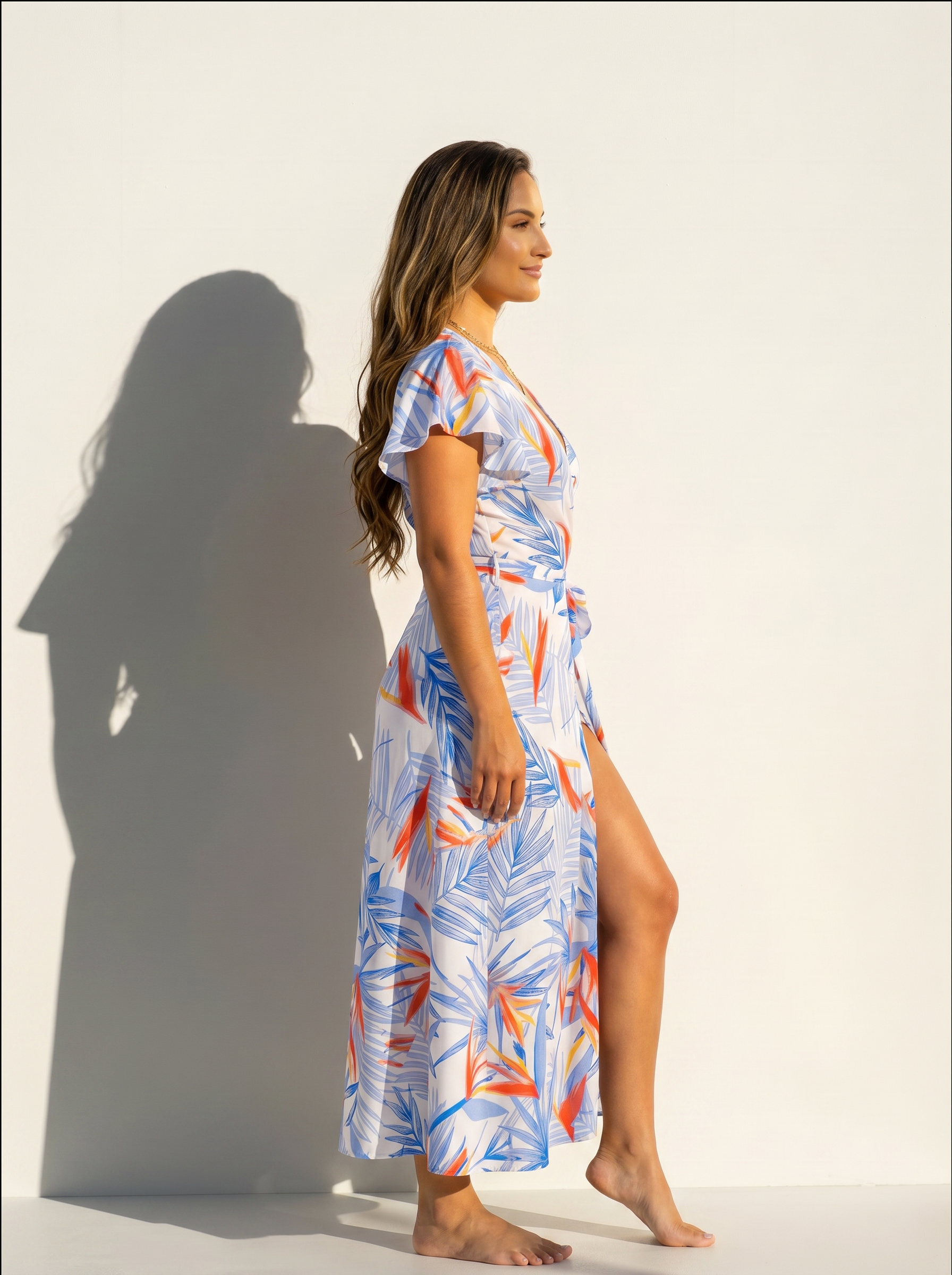 Side view of women wearing a birds of paradise print wrap dress on a white background