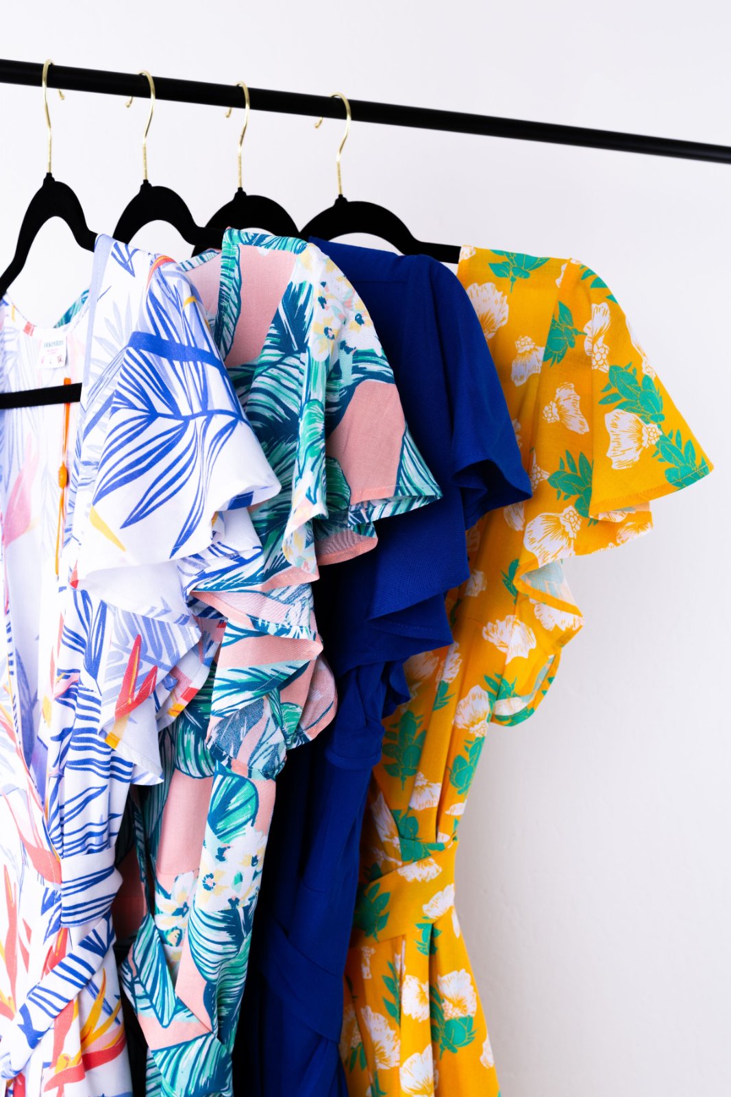 Colorful patterned clothes hanging on a rack against a white wall