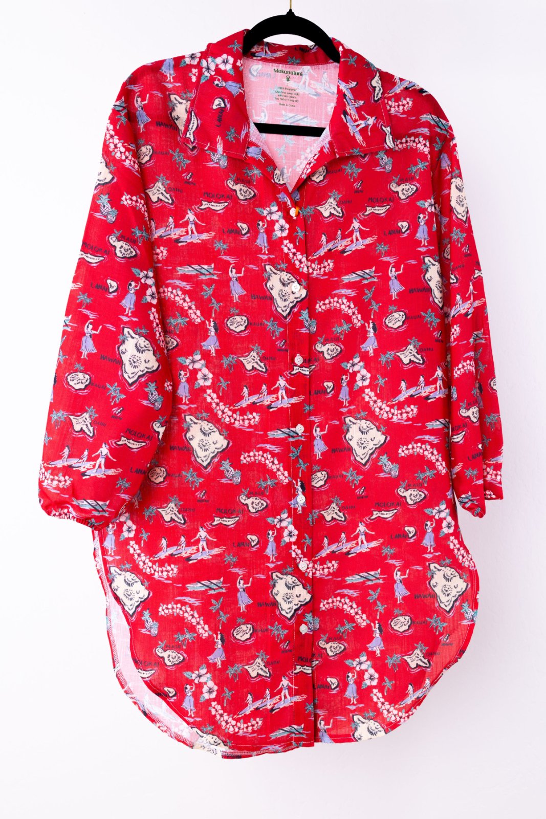Red patterned swim cover-up on a hanger against a white background