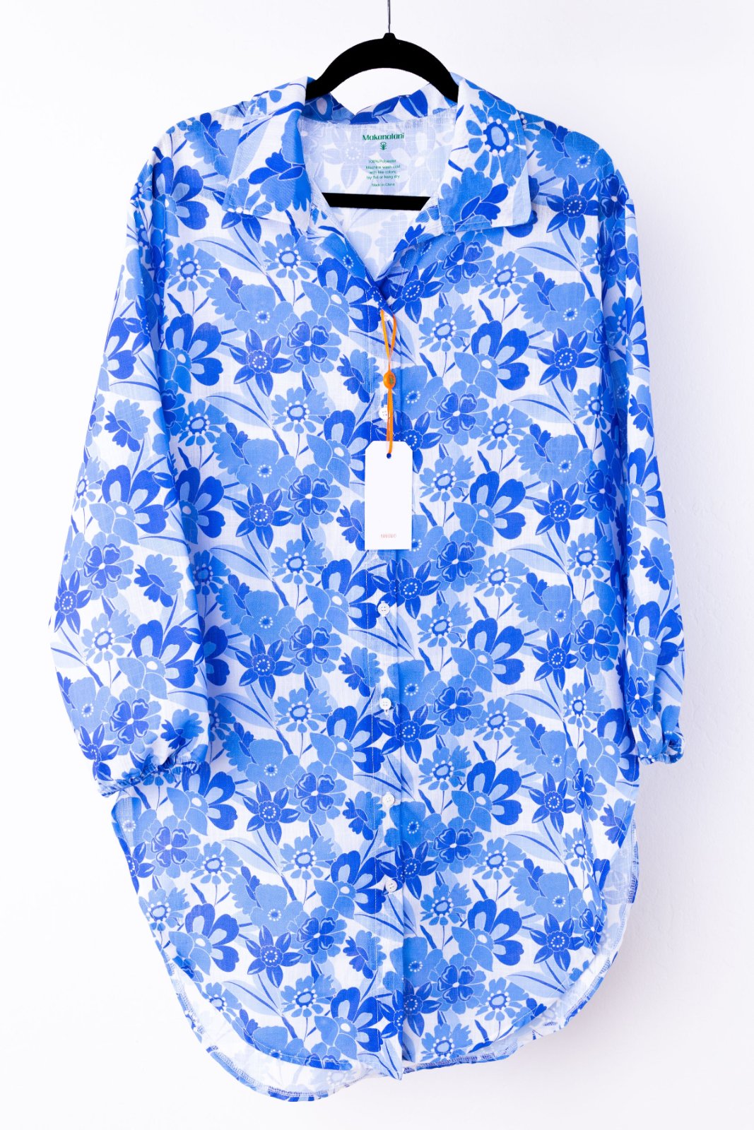 Blue floral patterned swim cover-up on a hanger with a white background