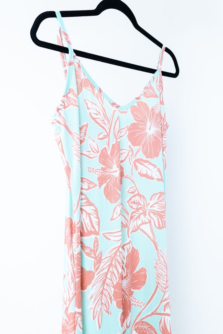 Floral dress with pink flowers on a light blue background, hanging on a black hanger.
