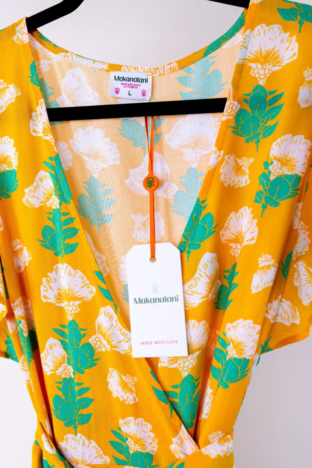 Yellow dress with floral pattern on a mannequin with a visible brand tag.