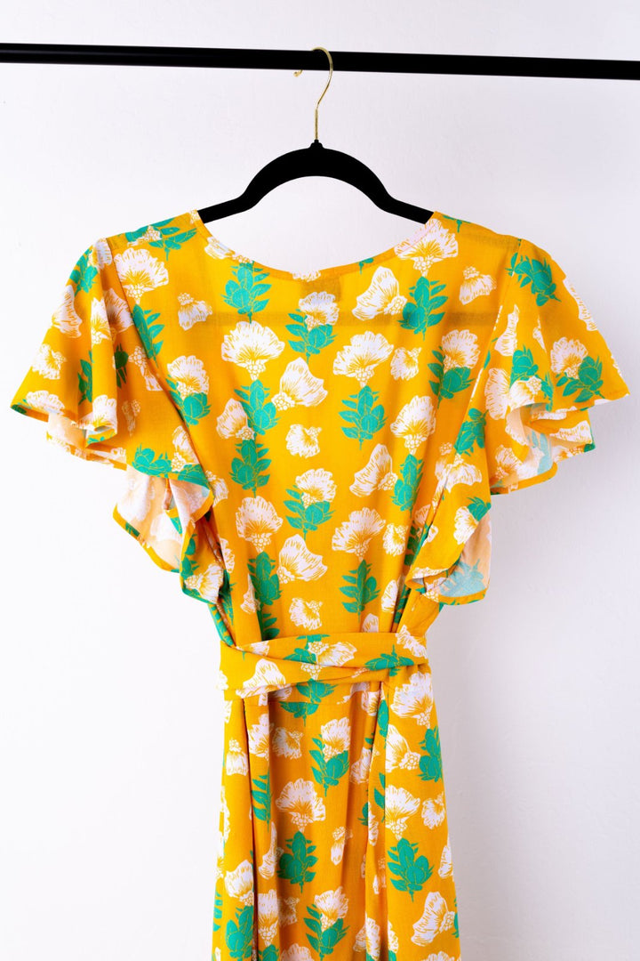 Yellow dress with floral pattern on a hanger against a white background