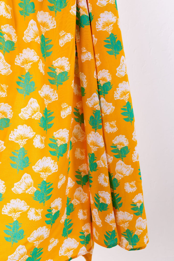 Yellow fabric with white floral and green leaf pattern on a white background