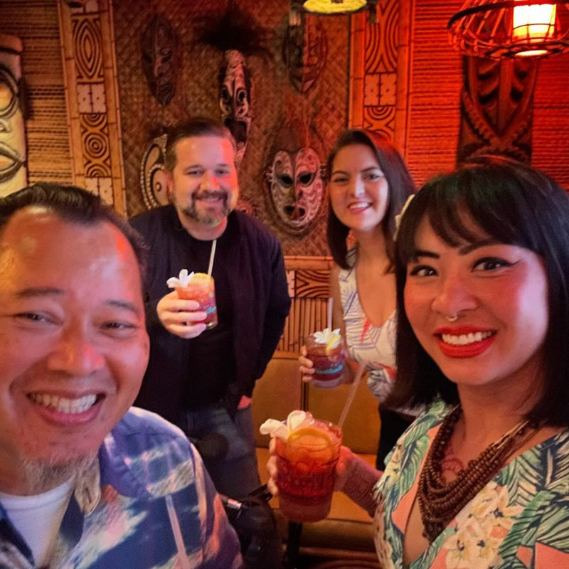 Group of people enjoying drinks in a tropical-themed bar.