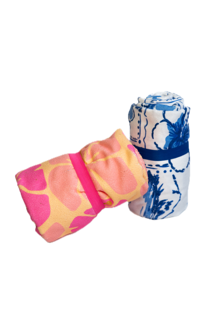 Two folded towels, one pink with floral pattern and one blue with white abstract design, on a white background.