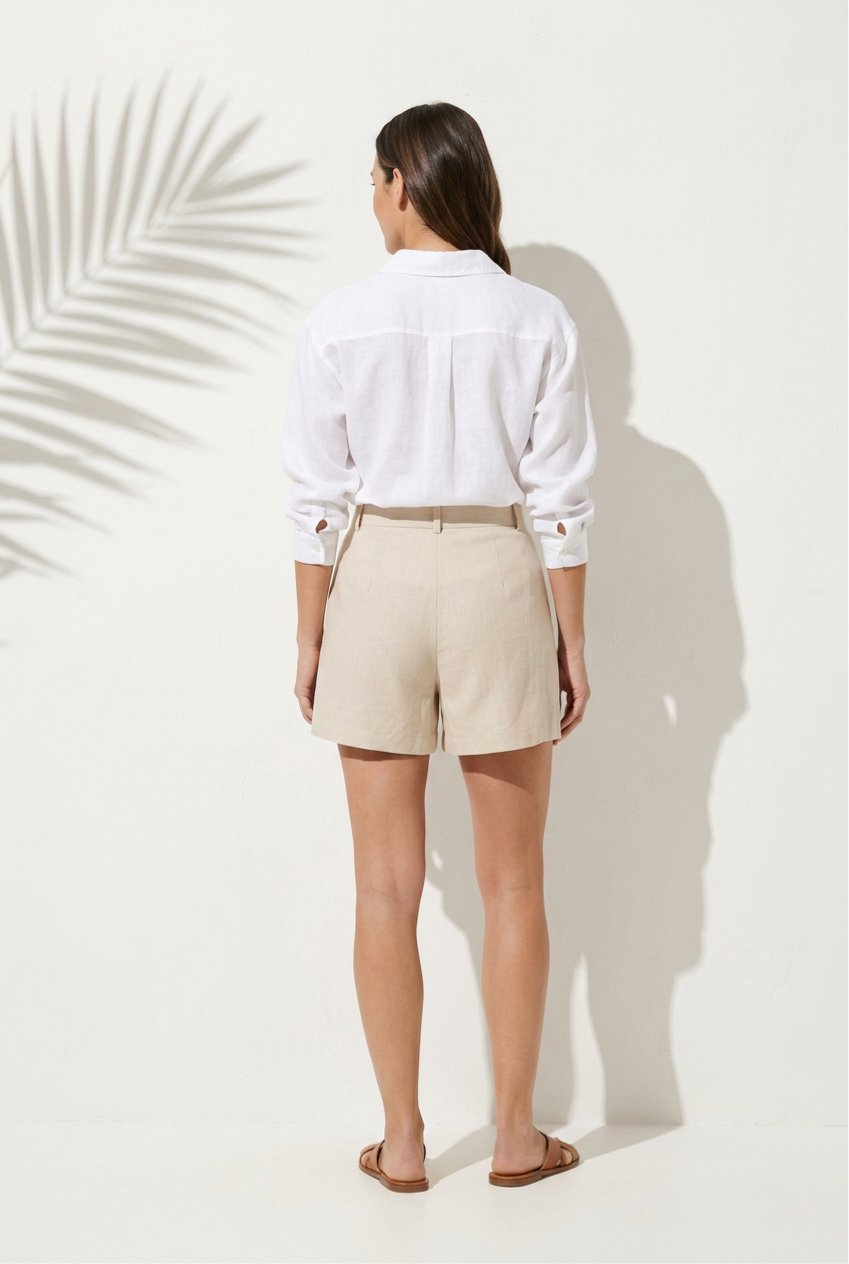 Person wearing a white shirt and beige shorts against a white background