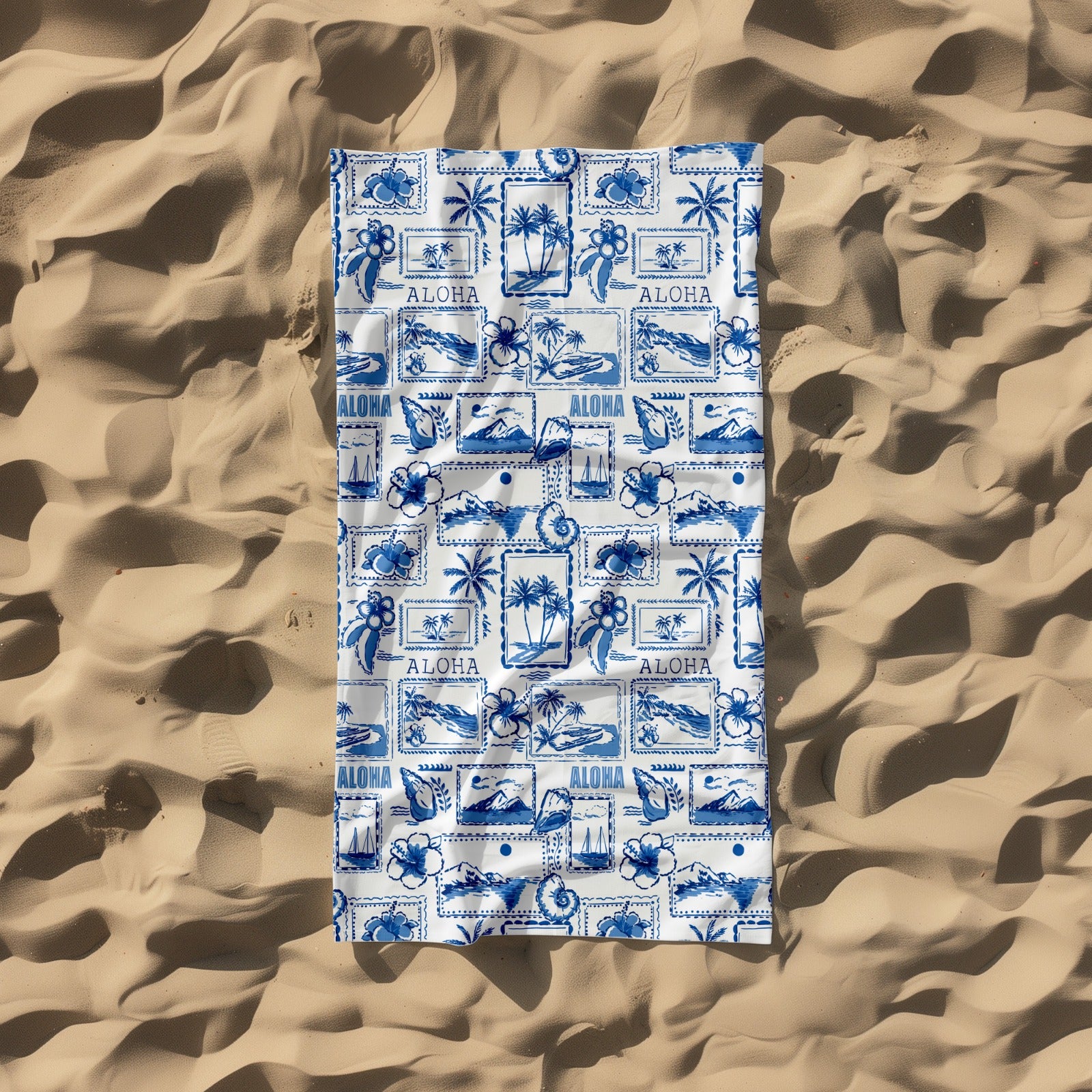 Blue and white patterned towel with 'Aloha' text on a sandy background