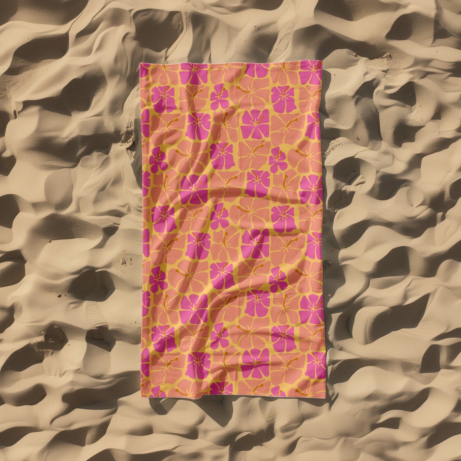 Pink and orange floral patterned towel on a sandy background